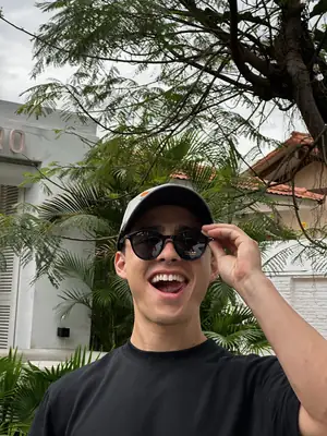 Sonriendo con gorra negra y lentes, polera negra UEBOS