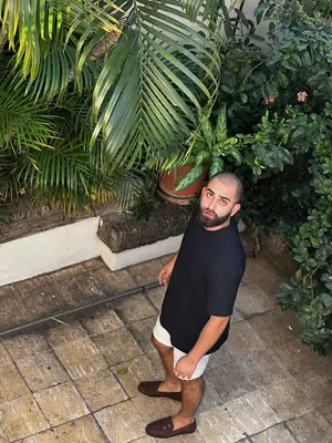 Con polera negra UEBOS en un patio de ladrillo entre plantas